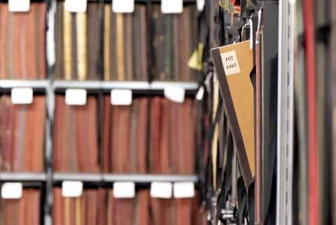A book leaning off the shelf of a library stack